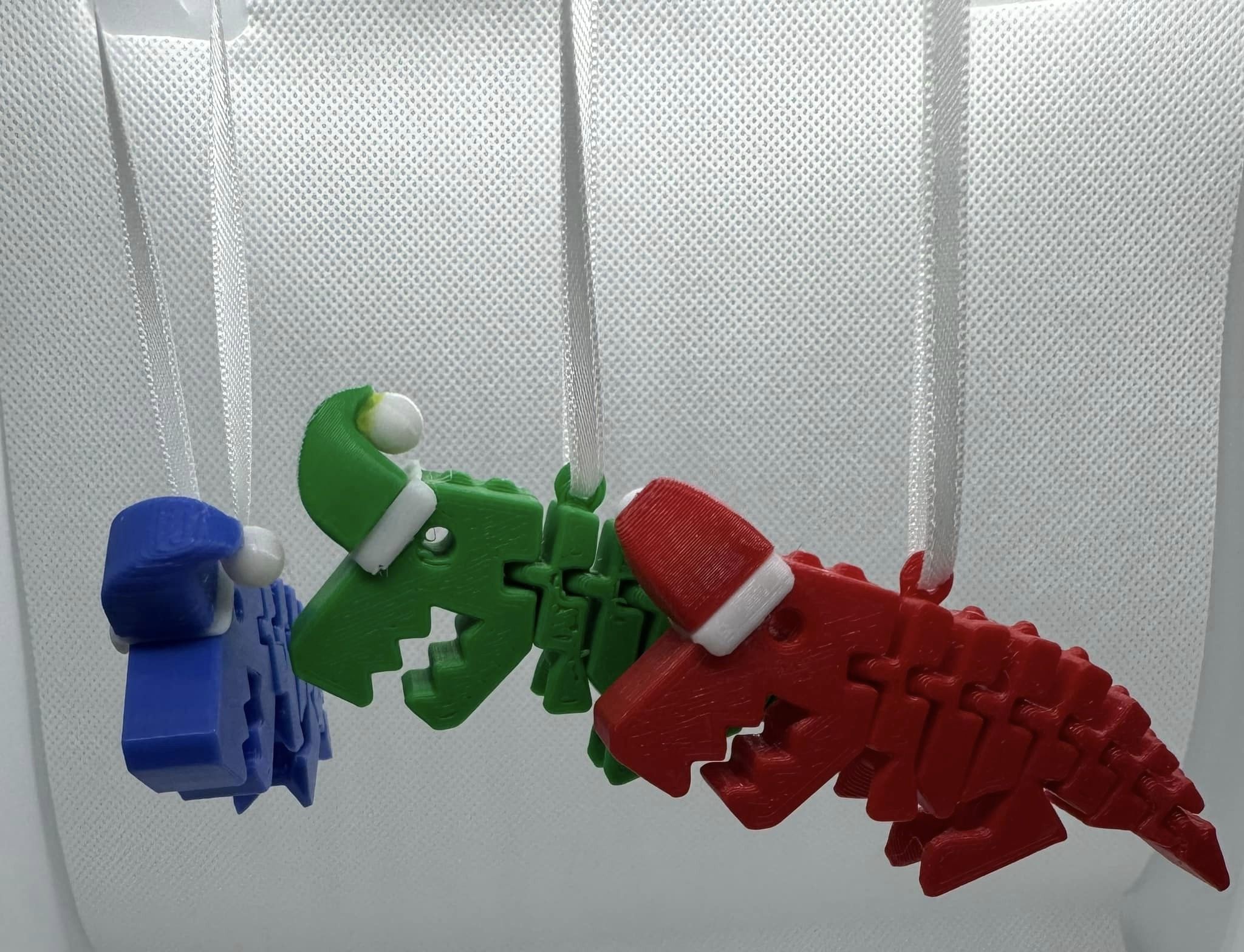 3D printed Dinosaur key chains wearing Santa hats.